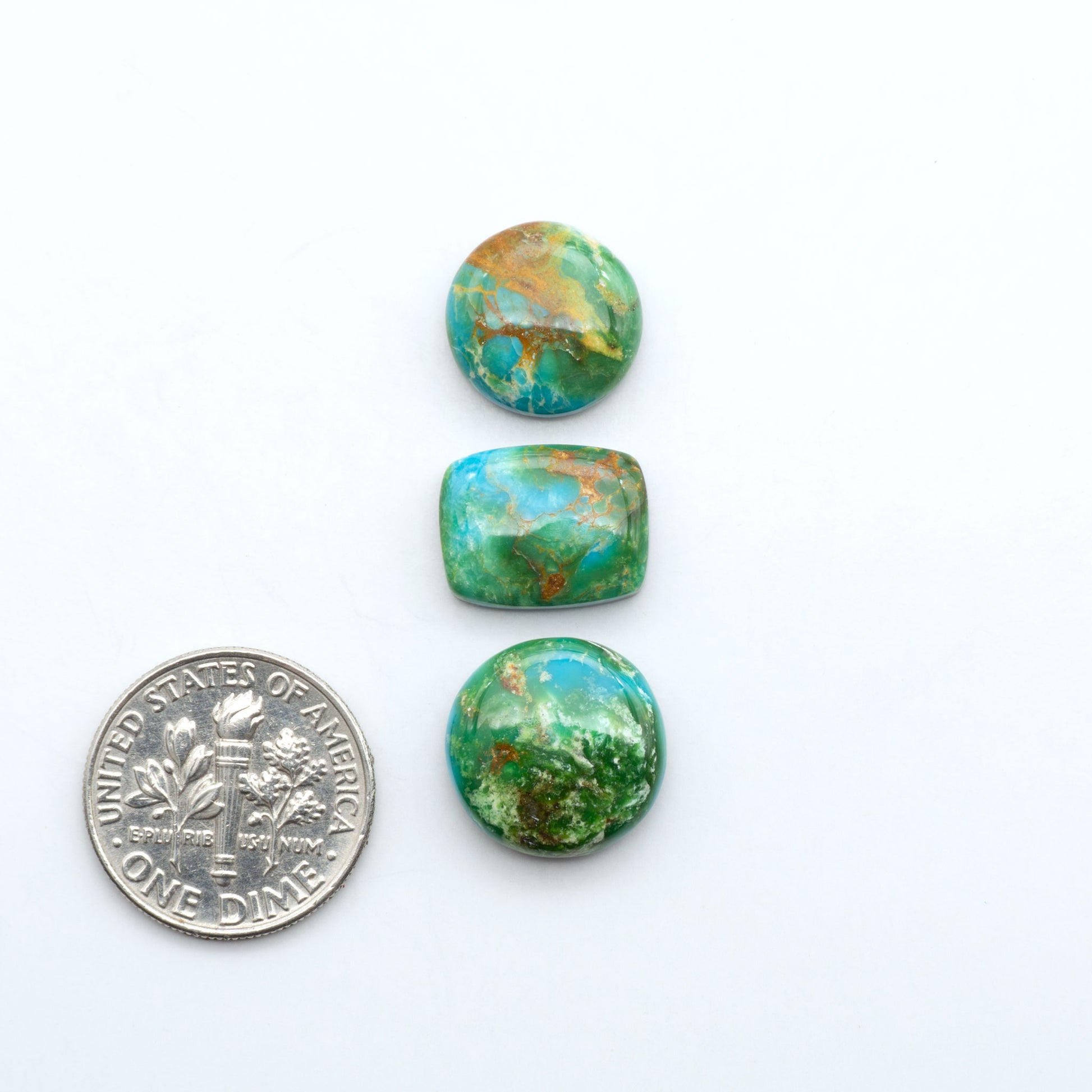 Sonoran Mountain Turquoise cabochons, blue-green color with natural matrix, polished stones on a white background, with a US dime for scale