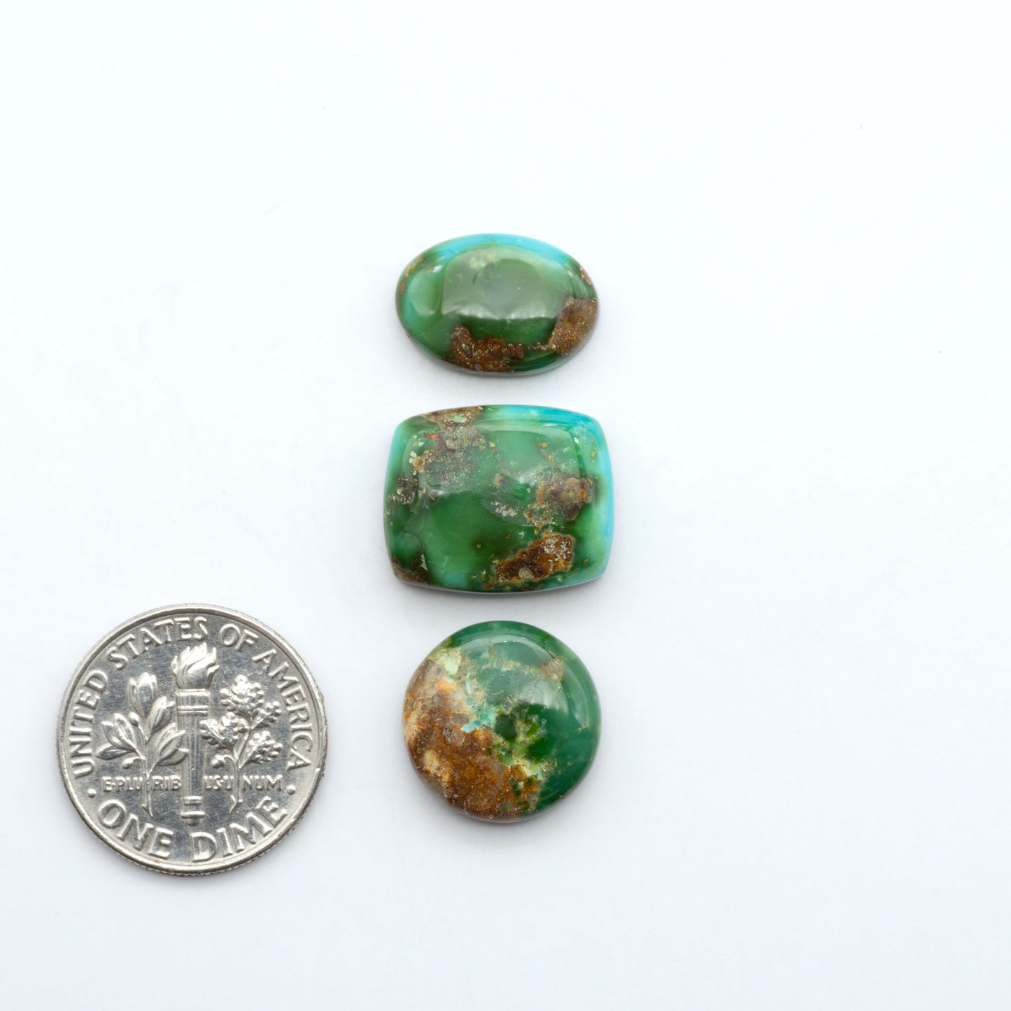 Sonoran Mountain Turquoise cabochons, blue-green color with natural matrix, polished stones on a white background, with a US dime for scale