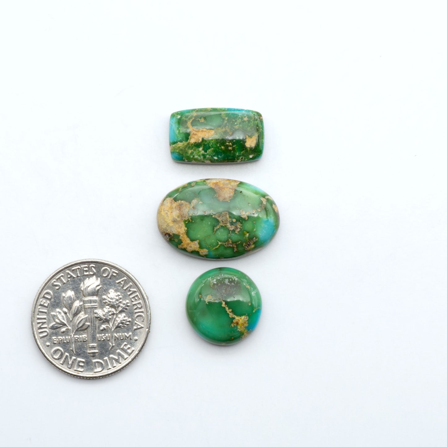 Sonoran Mountain Turquoise cabochons, blue-green color with natural matrix, polished stones on a white background, with a US dime for scale