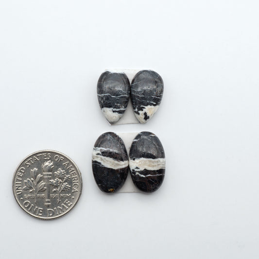 White Buffalo stone cabochons, white stone with black matrix, polished stones on a white background, with a US dime for scale