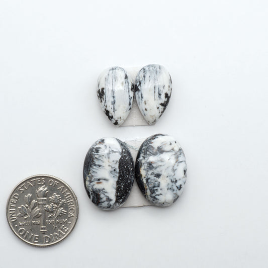 White Buffalo stone cabochons, white stone with black matrix, polished stones on a white background, with a US dime for scale