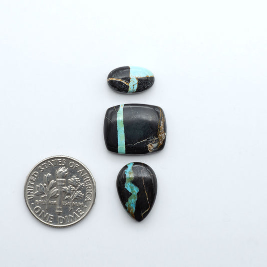 Black Jack turquoise cabochons, blue-green color with black matrix, polished stones on a white background with a US dime for scale