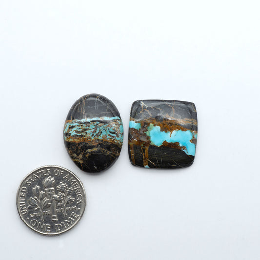 Black Jack turquoise cabochons, blue-green color with black matrix, polished stones on a white background with a US dime for scale