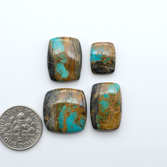 Black Jack turquoise cabochons, blue-green color with black matrix, polished stones on a white background with a US dime for scale