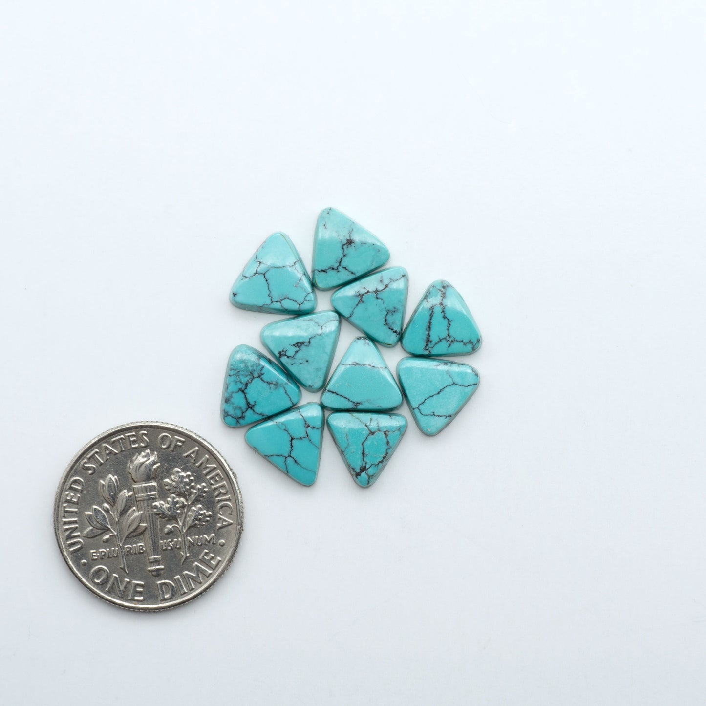 Hubei Cloud Mountain Turquoise cabochons, blue and green color with black matrix, polished stones on a white background with a US dime for scale