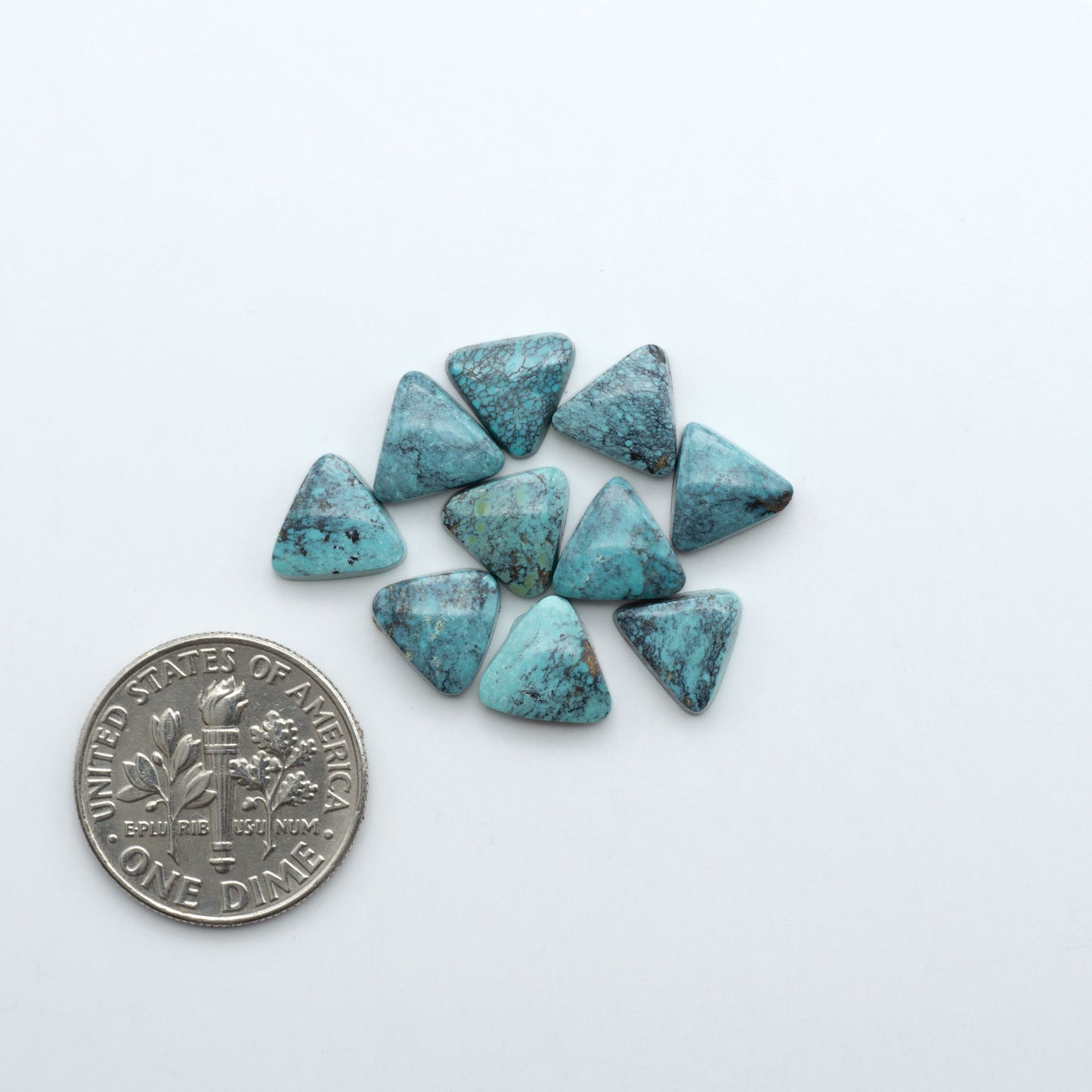 Hubei Cloud Mountain Turquoise cabochons, blue and green color with black matrix, polished stones on a white background with a US dime for scale