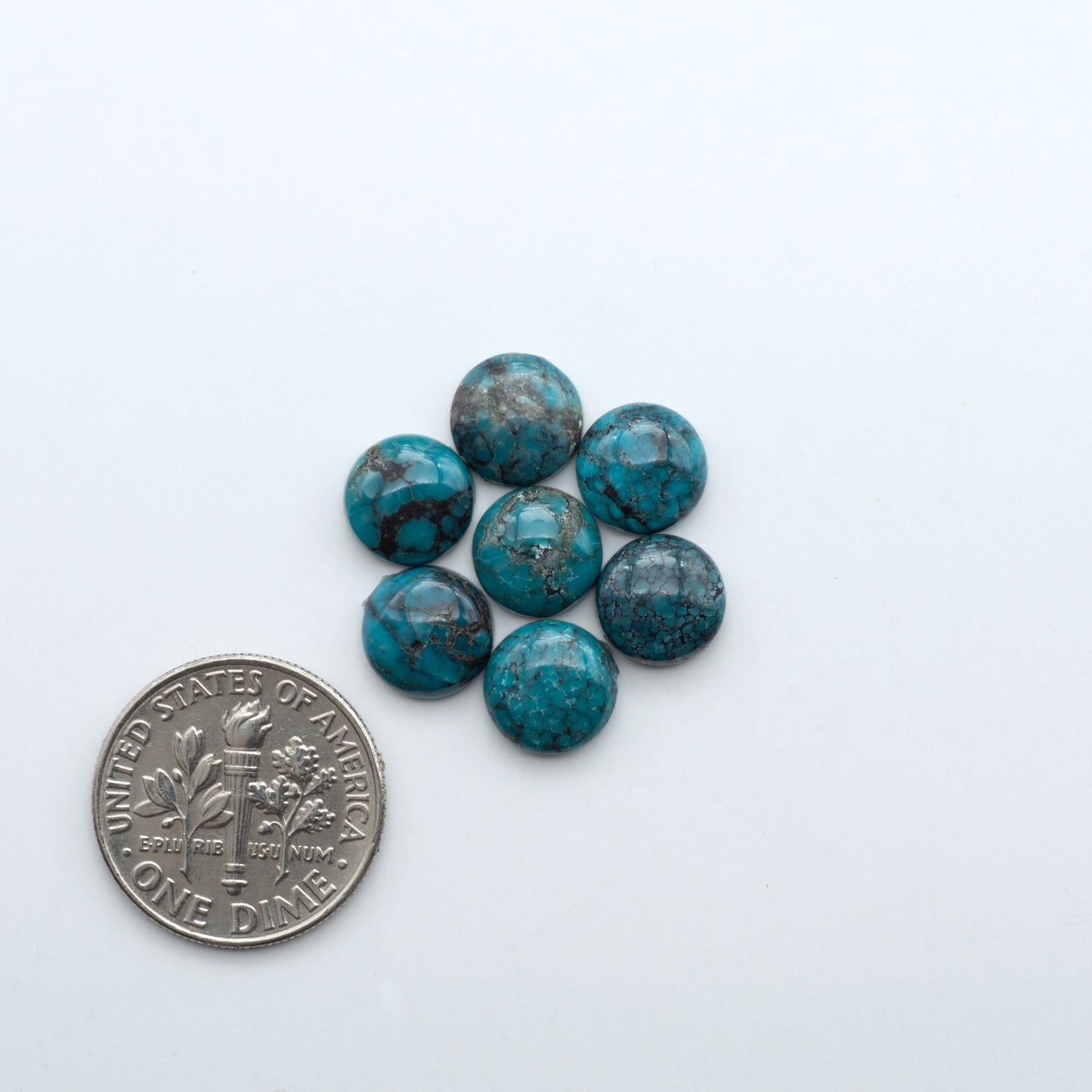 Hubei Cloud Mountain Turquoise cabochons, blue and green color with black matrix, polished stones on a white background with a US dime for scale