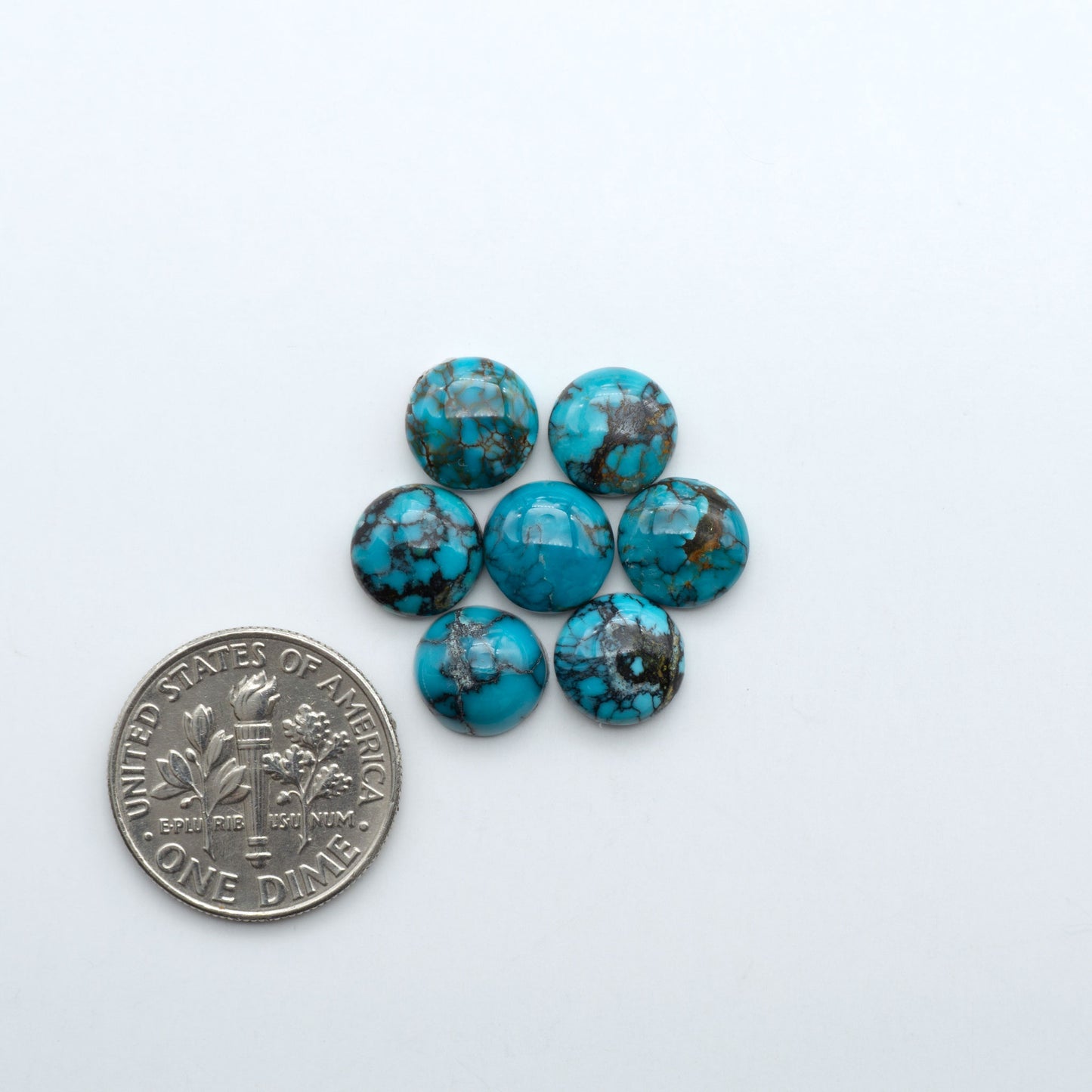 Hubei Cloud Mountain Turquoise cabochons, blue and green color with black matrix, polished stones on a white background with a US dime for scale