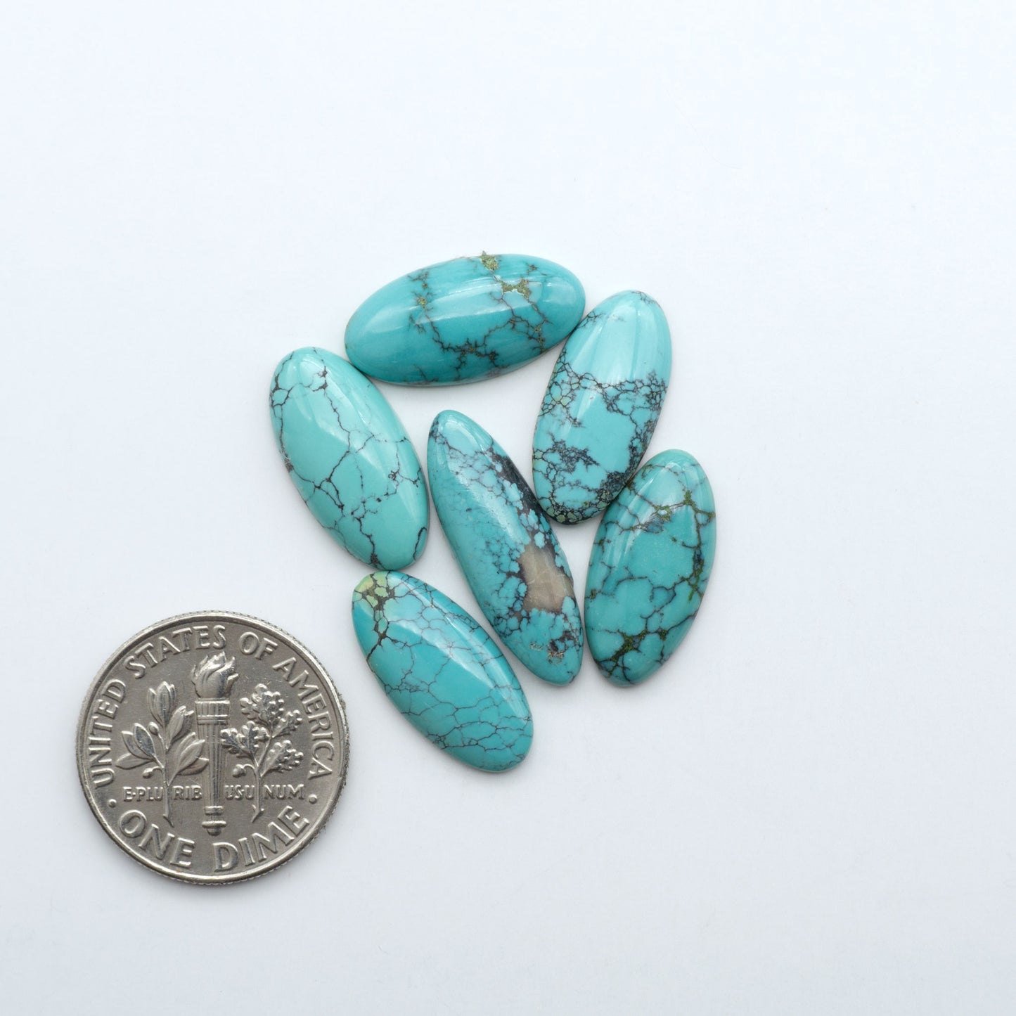 Hubei Cloud Mountain Turquoise cabochons, blue and green color with black matrix, polished stones on a white background with a US dime for scale