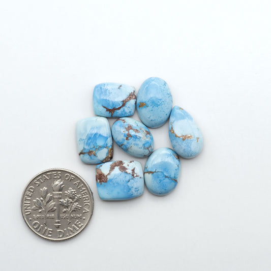 Golden Hills Turquoise cabochons, icy blue to lavender tones with chocolate matrix, polished stones on a white background with a US dime for scale