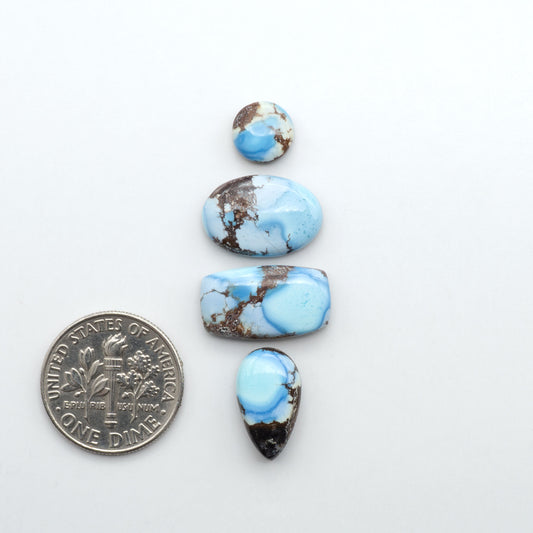 Golden Hills Turquoise cabochons, icy blue to lavender tones with chocolate matrix, polished stones on a white background with a US dime for scale