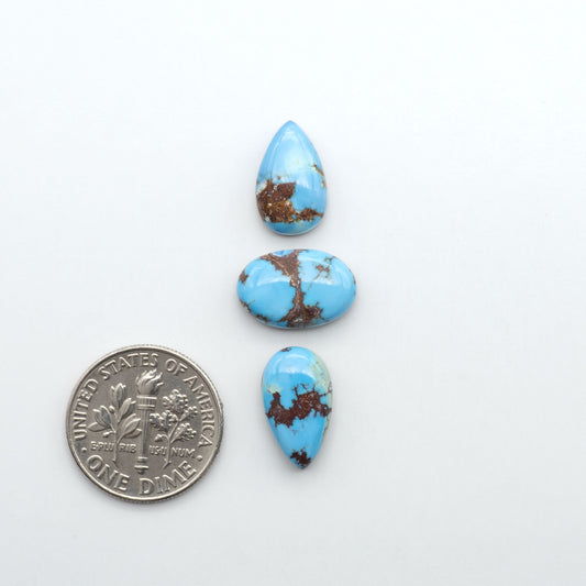 Golden Hills Turquoise cabochons, icy blue to lavender tones with chocolate matrix, polished stones on a white background with a US dime for scale