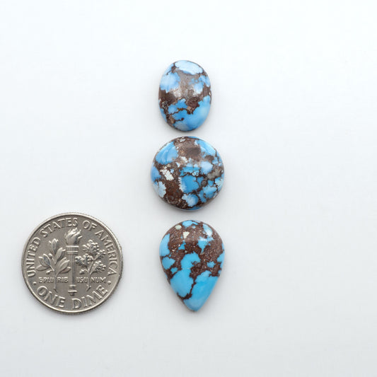 Golden Hills Turquoise cabochons, icy blue to lavender tones with chocolate matrix, polished stones on a white background with a US dime for scale
