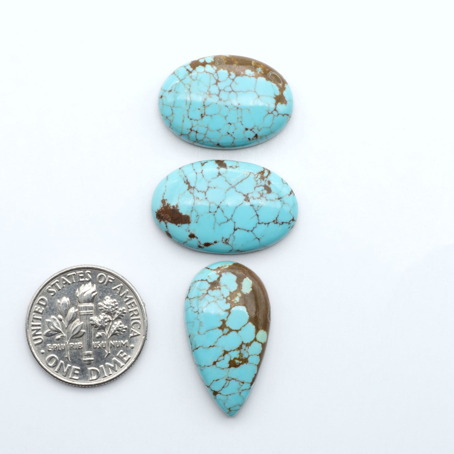 Number 8 Turquoise cabochons, blue and green color with brown matrix, polished stones on a white background, with a US dime for scale