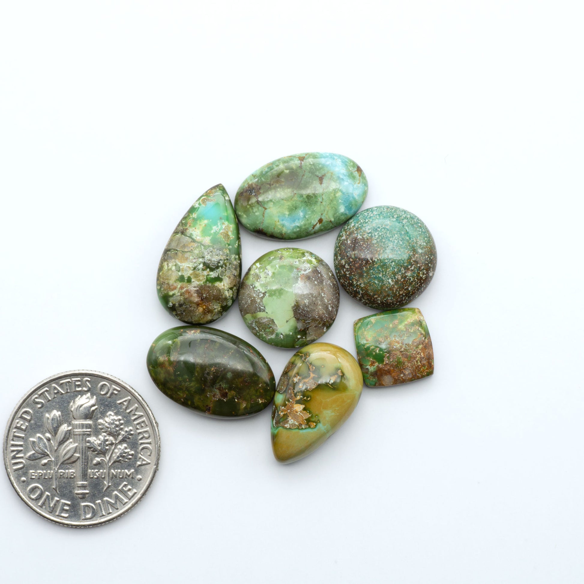 Sonoran Mountain Turquoise cabochons, blue-green color with natural matrix, polished stones on a white background, with a US dime for scale