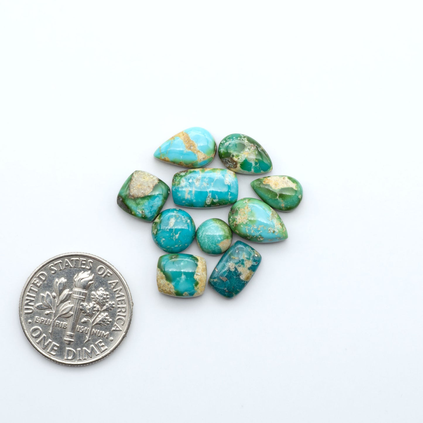 Sonoran Mountain Turquoise cabochons, blue-green color with natural matrix, polished stones on a white background, with a US dime for scale
