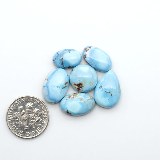 Golden Hills Turquoise cabochons, icy blue to lavender tones with chocolate matrix, polished stones on a white background with a US dime for scale