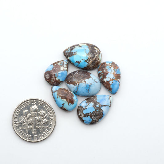 Golden Hills Turquoise cabochons, icy blue to lavender tones with chocolate matrix, polished stones on a white background with a US dime for scale
