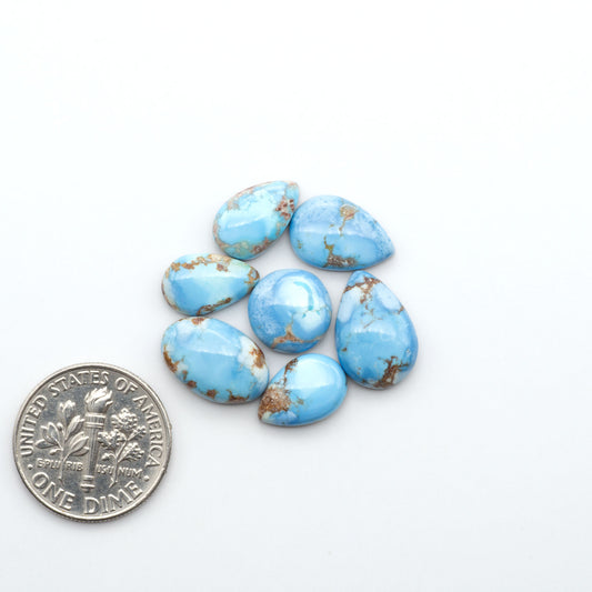 Golden Hills Turquoise cabochons, icy blue to lavender tones with chocolate matrix, polished stones on a white background with a US dime for scale