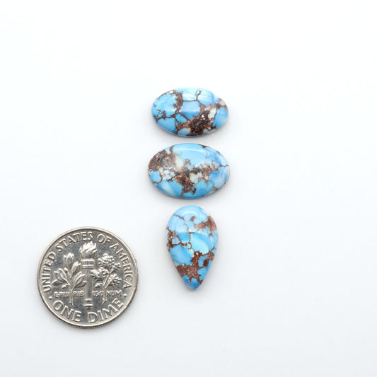 Golden Hills Turquoise cabochons, icy blue to lavender tones with chocolate matrix, polished stones on a white background with a US dime for scale