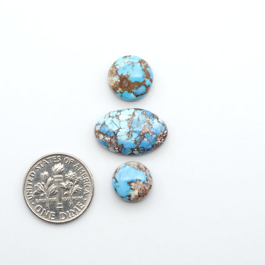 Golden Hills Turquoise cabochons, icy blue to lavender tones with chocolate matrix, polished stones on a white background with a US dime for scale