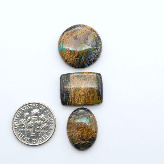 Black Jack turquoise cabochons, blue-green color with black matrix, polished stones on a white background with a US dime for scale
