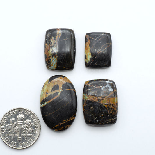 Black Jack turquoise cabochons, blue-green color with black matrix, polished stones on a white background with a US dime for scale