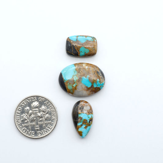 Black Jack turquoise cabochons, blue-green color with black matrix, polished stones on a white background with a US dime for scale