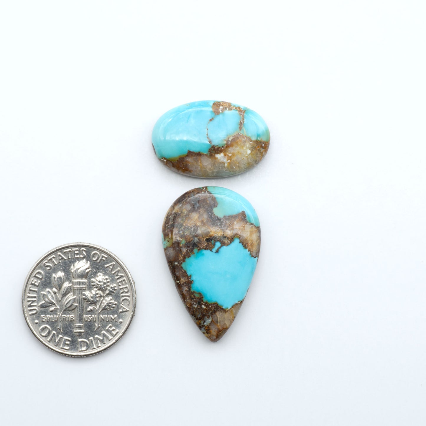Black Jack turquoise cabochons, blue-green color with black matrix, polished stones on a white background with a US dime for scale