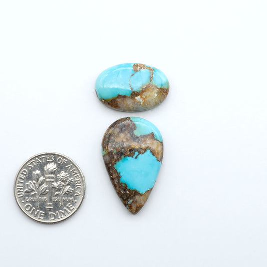 Black Jack turquoise cabochons, blue-green color with black matrix, polished stones on a white background with a US dime for scale