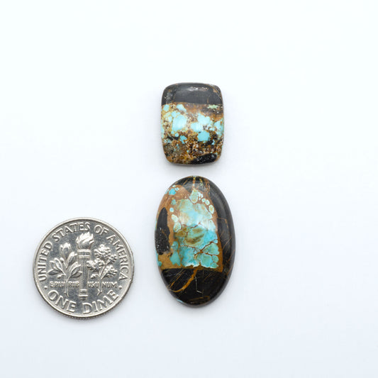 Black Jack turquoise cabochons, blue-green color with black matrix, polished stones on a white background with a US dime for scale