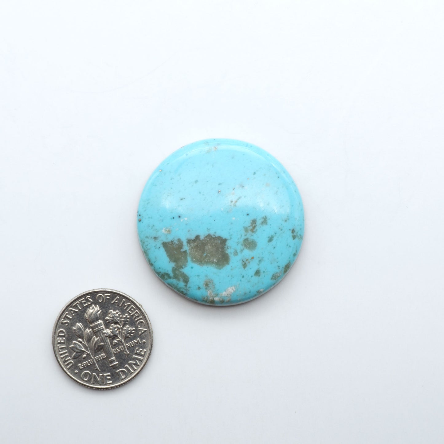 Nacozari Turquoise cabochons, blue to greenish-blue gemstones with black or brown matrix and pyrite on a white background with a US dime for scale