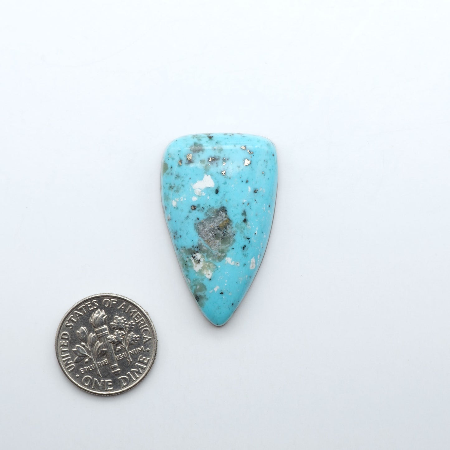 Nacozari Turquoise cabochons, blue to greenish-blue gemstones with black or brown matrix and pyrite on a white background with a US dime for scale