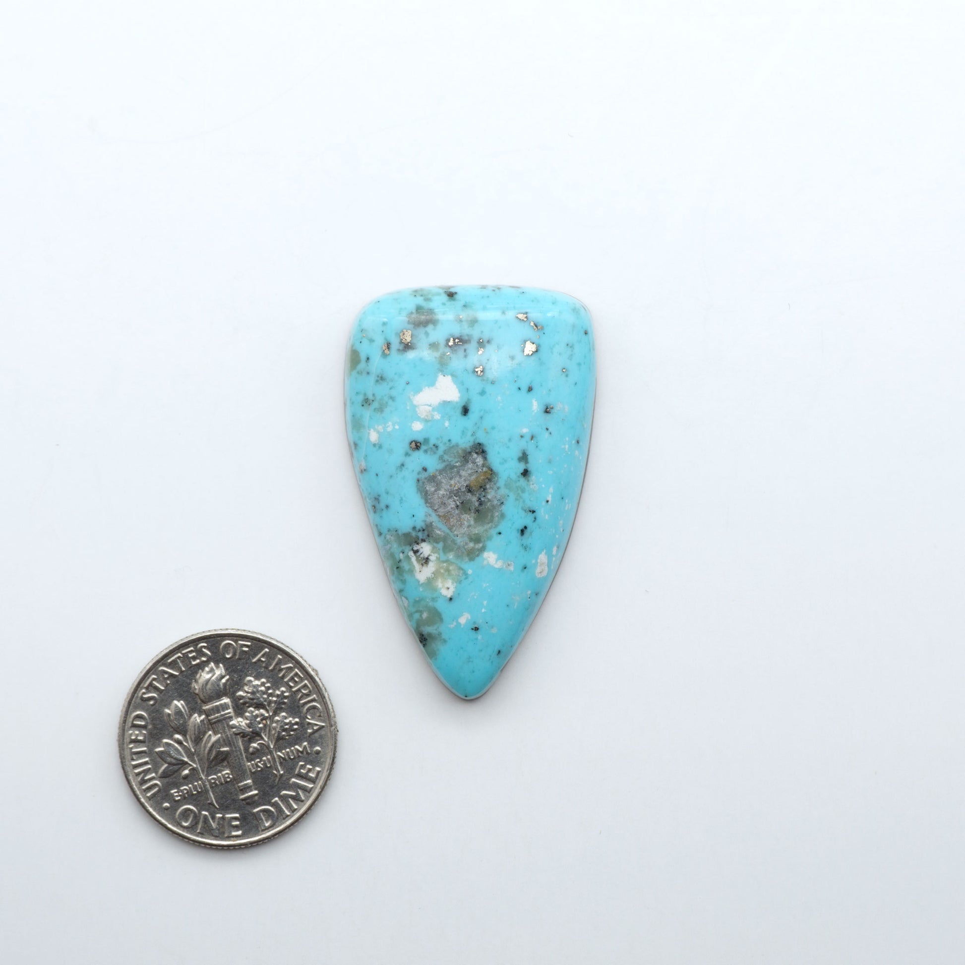 Nacozari Turquoise cabochons, blue to greenish-blue gemstones with black or brown matrix and pyrite on a white background with a US dime for scale