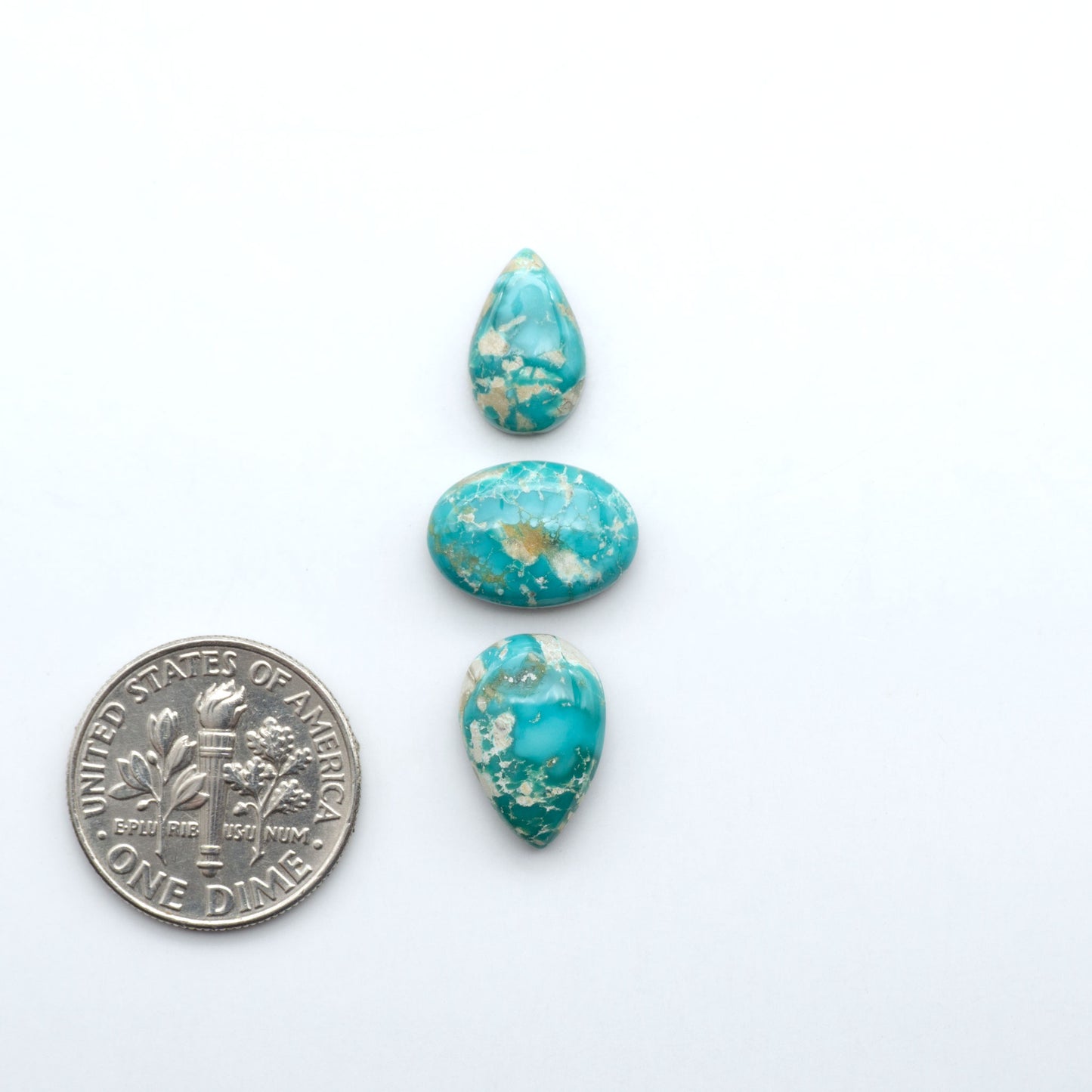 Fox Turquoise cabochons, polished gemstones with natural matrix on a white background, with a US dime for scale