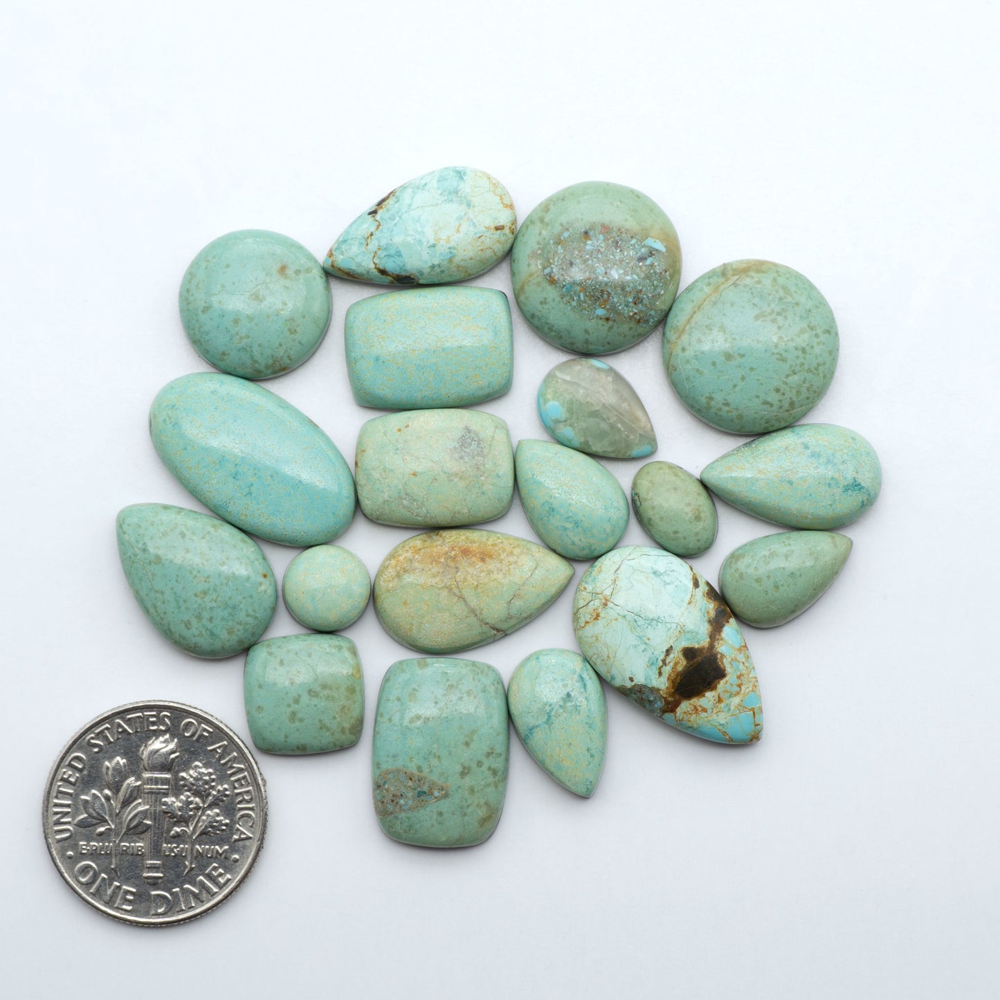 Number 8 Turquoise cabochons, blue and green color with brown matrix, polished stones on a white background, with a US dime for scale