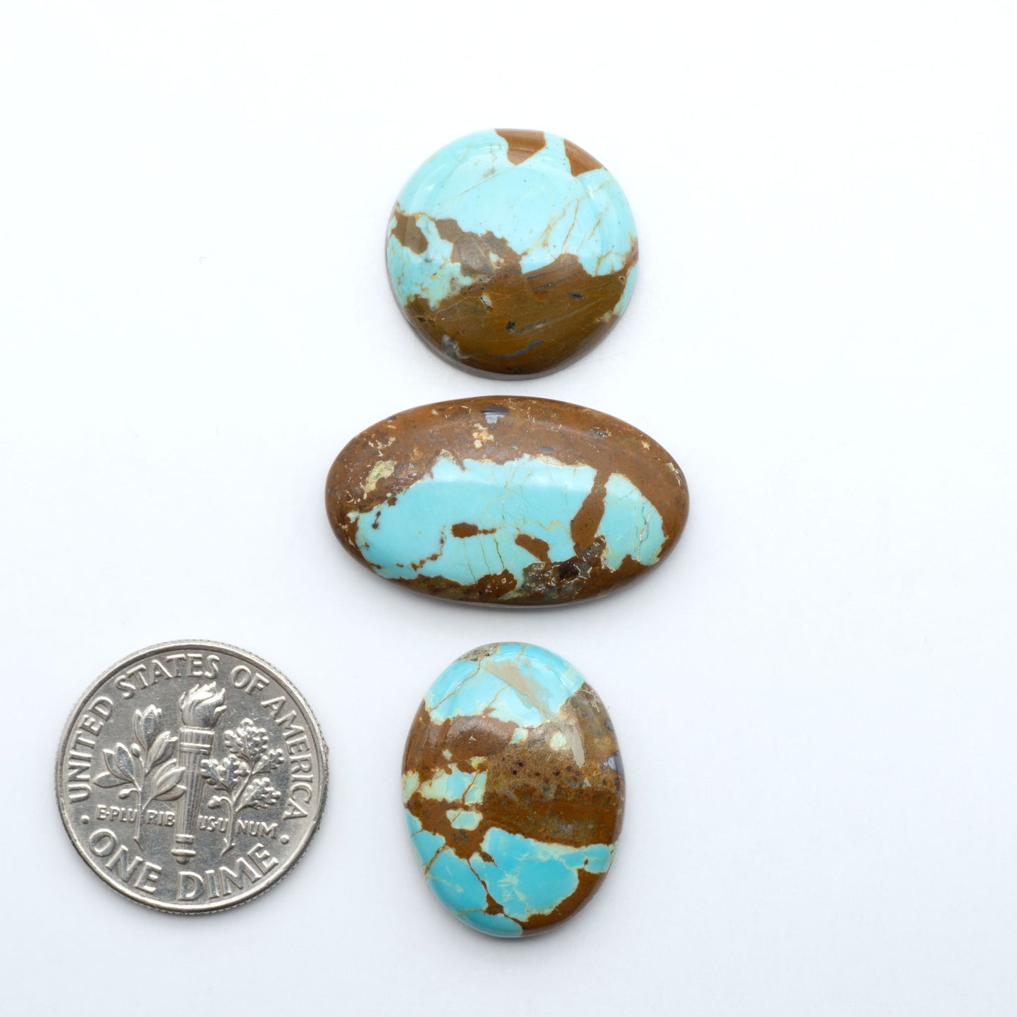 Number 8 Turquoise cabochons, blue and green color with brown matrix, polished stones on a white background, with a US dime for scale