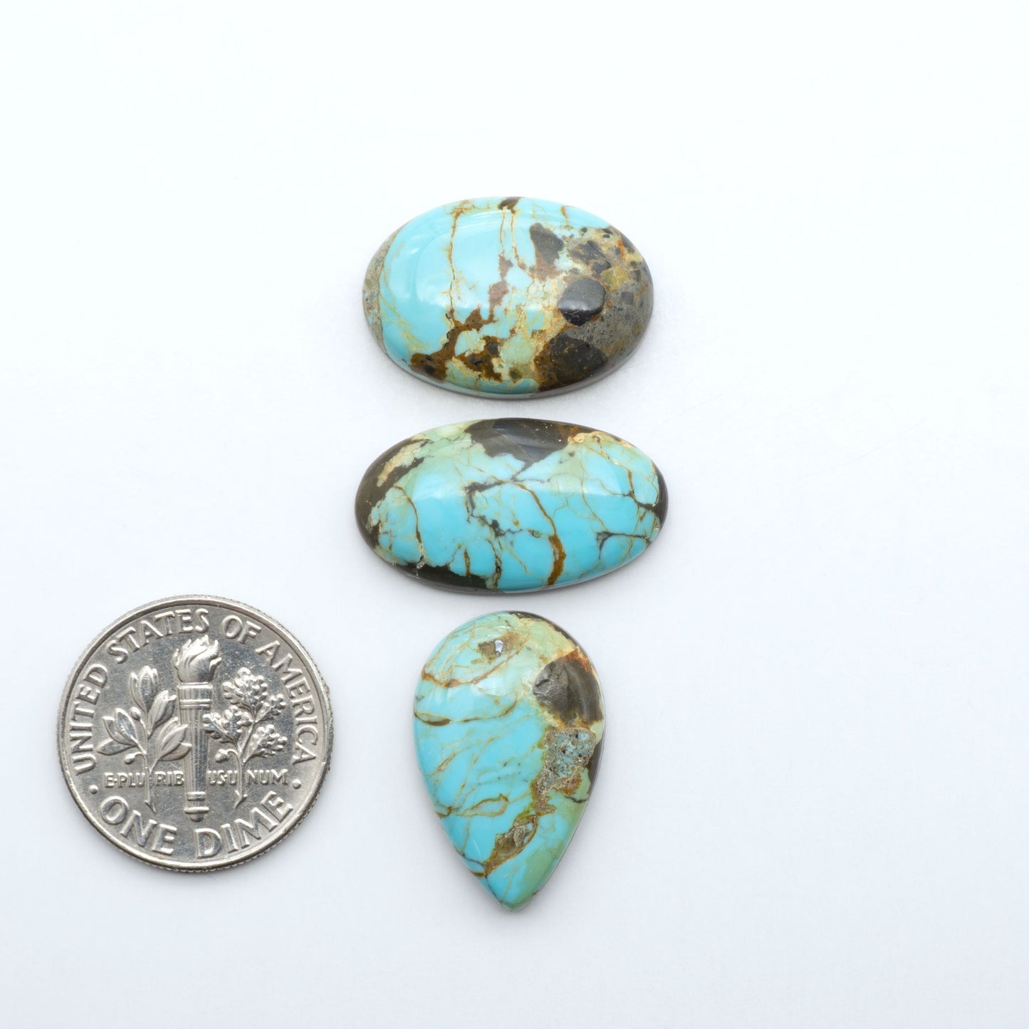 Number 8 Turquoise cabochons, blue and green color with brown matrix, polished stones on a white background, with a US dime for scale
