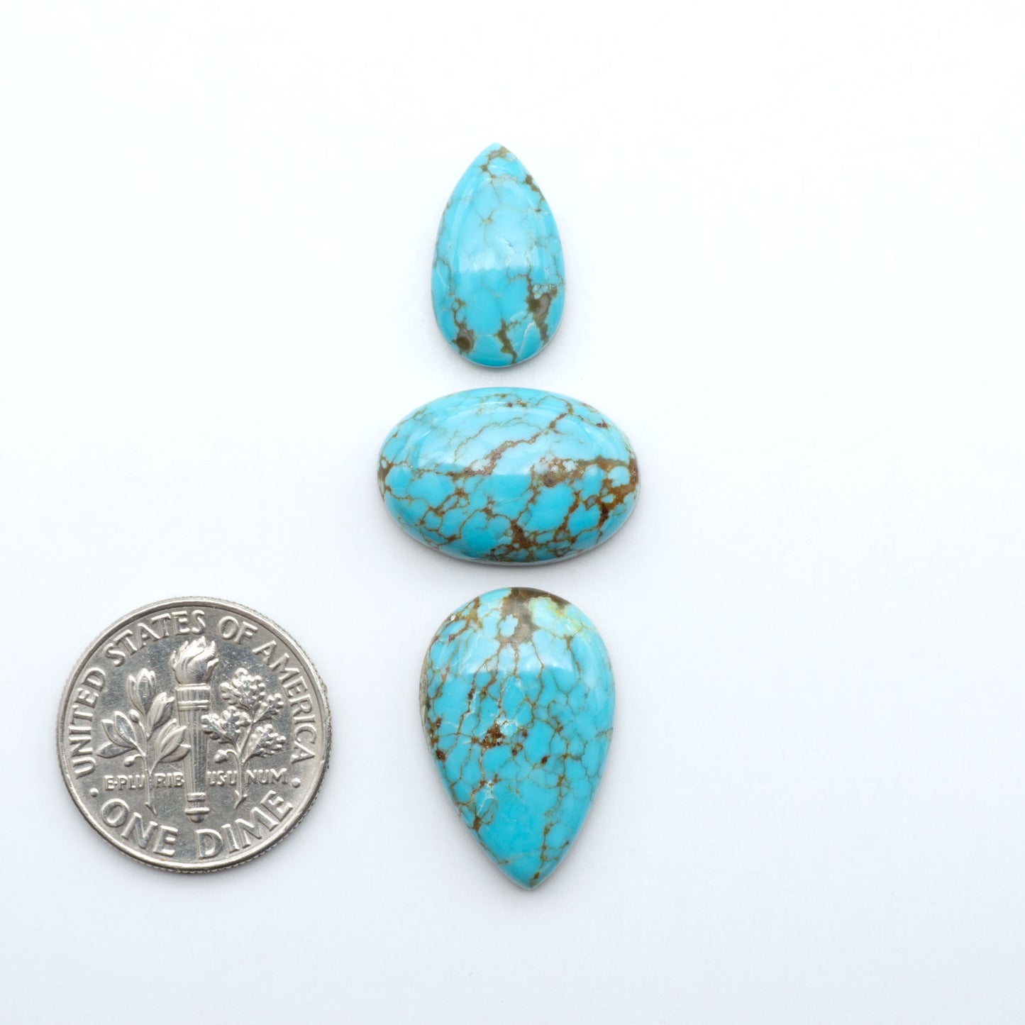 Number 8 Turquoise cabochons, blue and green color with brown matrix, polished stones on a white background, with a US dime for scale