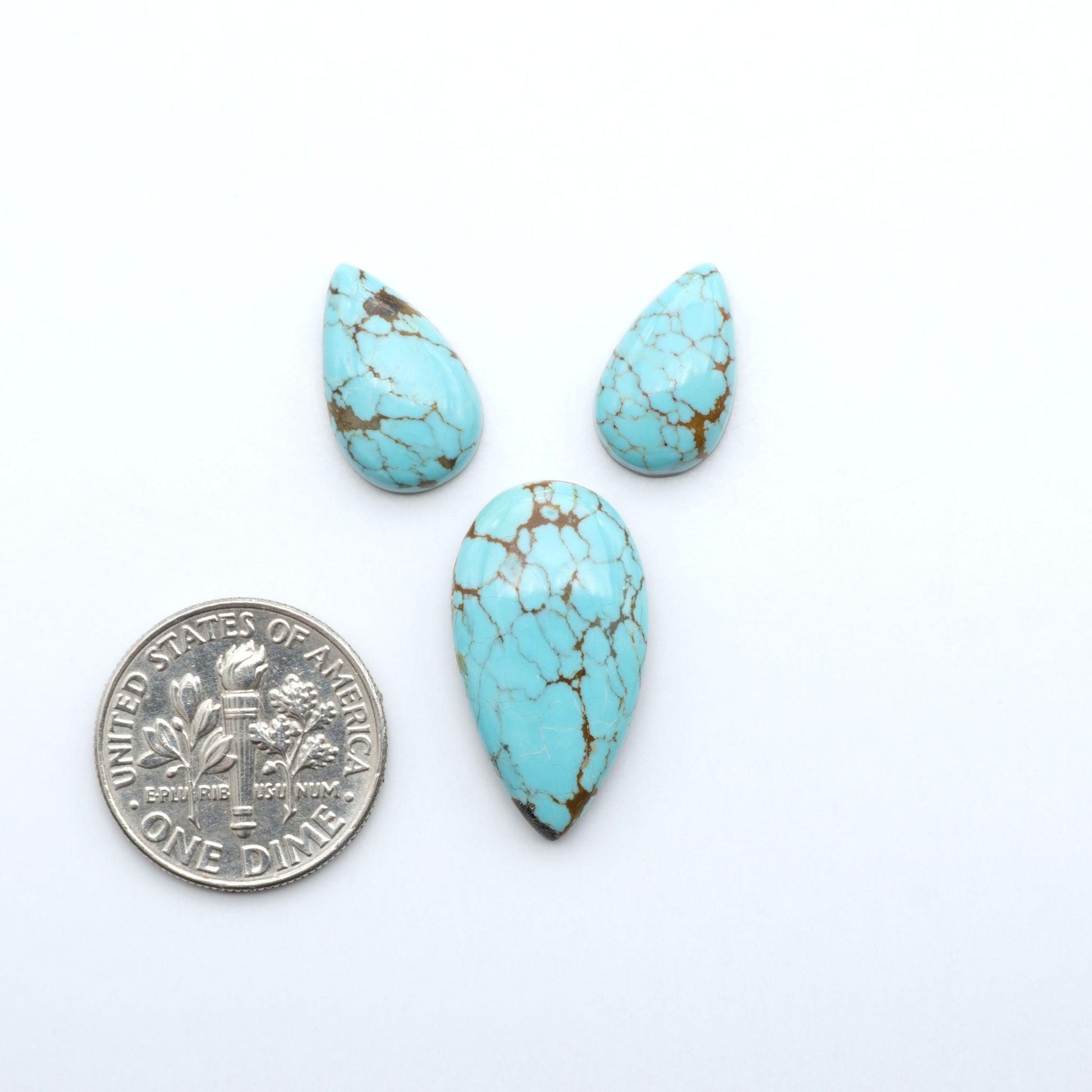 Number 8 Turquoise cabochons, blue and green color with brown matrix, polished stones on a white background, with a US dime for scale