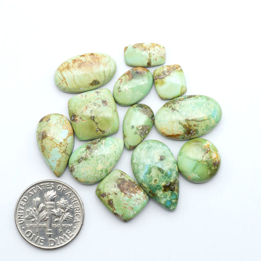 Sonoran Mountain Turquoise cabochons, blue-green color with natural matrix, polished stones on a white background, with a US dime for scale
