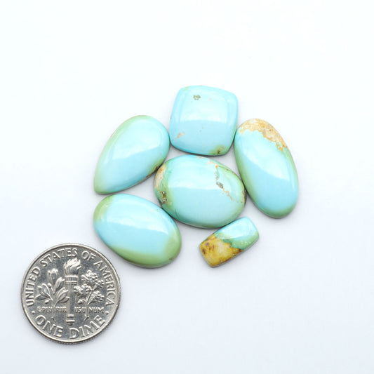 Sonoran Mountain Turquoise cabochons, blue-green color with natural matrix, polished stones on a white background, with a US dime for scale