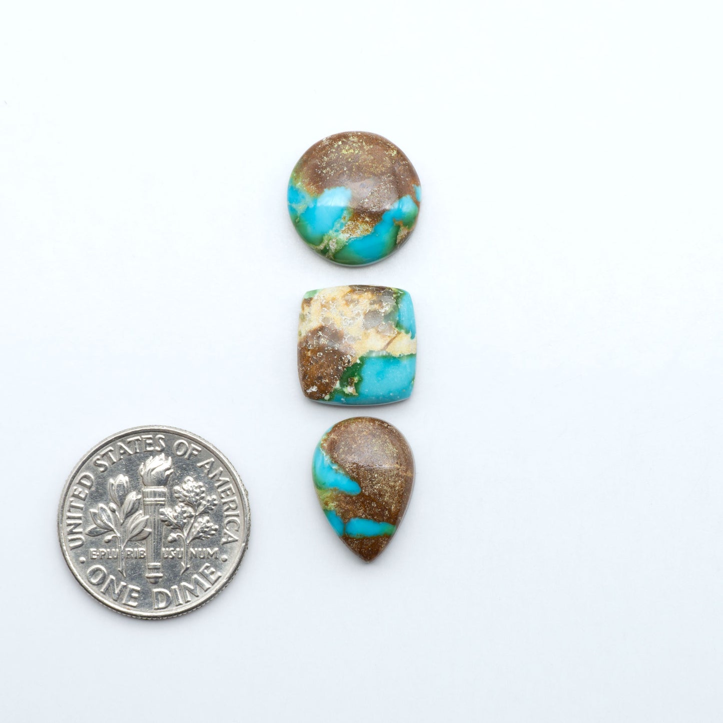 Sonoran Mountain Turquoise cabochons, blue-green color with natural matrix, polished stones on a white background, with a US dime for scale