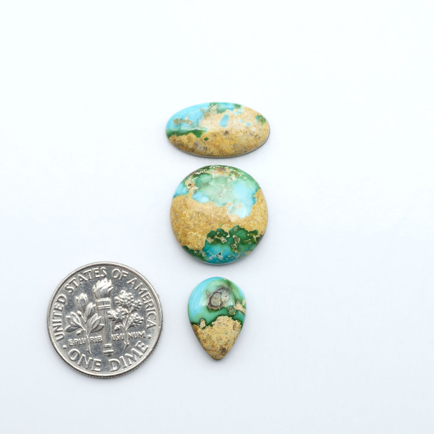 Sonoran Mountain Turquoise cabochons, blue-green color with natural matrix, polished stones on a white background, with a US dime for scale