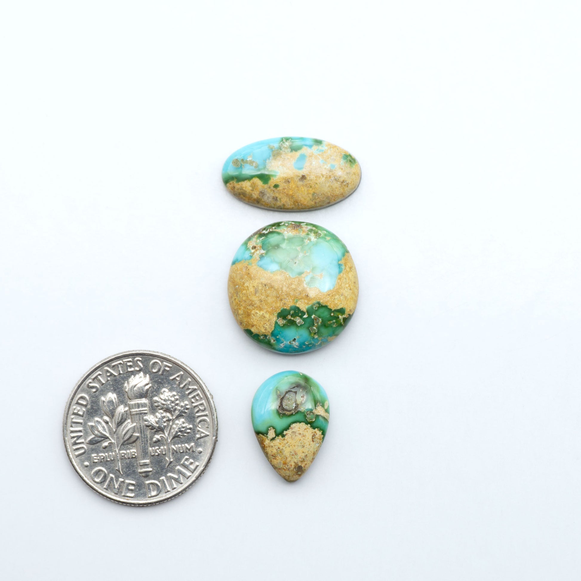 Sonoran Mountain Turquoise cabochons, blue-green color with natural matrix, polished stones on a white background, with a US dime for scale