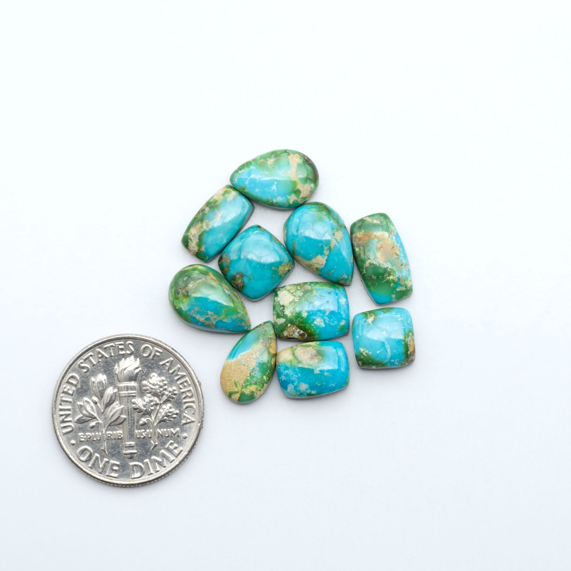 Sonoran Mountain Turquoise cabochons, blue-green color with natural matrix, polished stones on a white background, with a US dime for scale