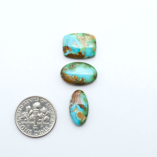 Sonoran Mountain Turquoise cabochons, blue-green color with natural matrix, polished stones on a white background, with a US dime for scale