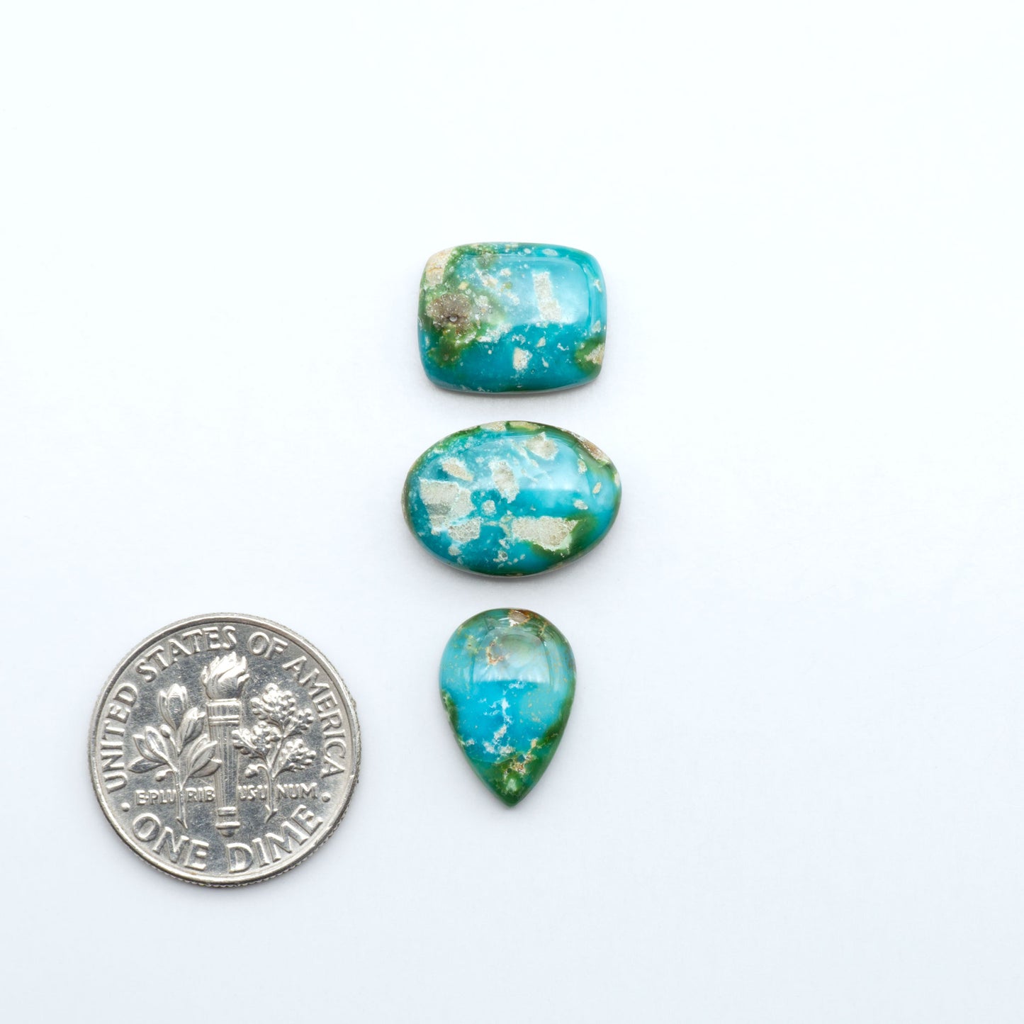 Sonoran Mountain Turquoise cabochons, blue-green color with natural matrix, polished stones on a white background, with a US dime for scale