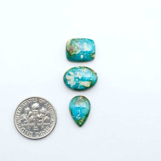 Sonoran Mountain Turquoise cabochons, blue-green color with natural matrix, polished stones on a white background, with a US dime for scale