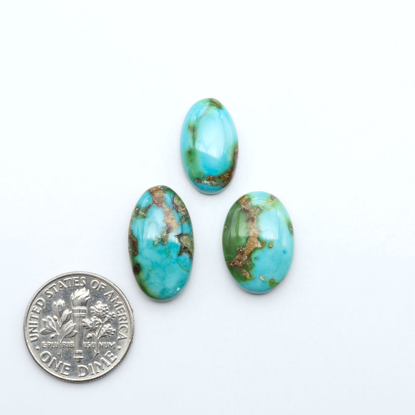 Sonoran Mountain Turquoise cabochons, blue-green color with natural matrix, polished stones on a white background, with a US dime for scale